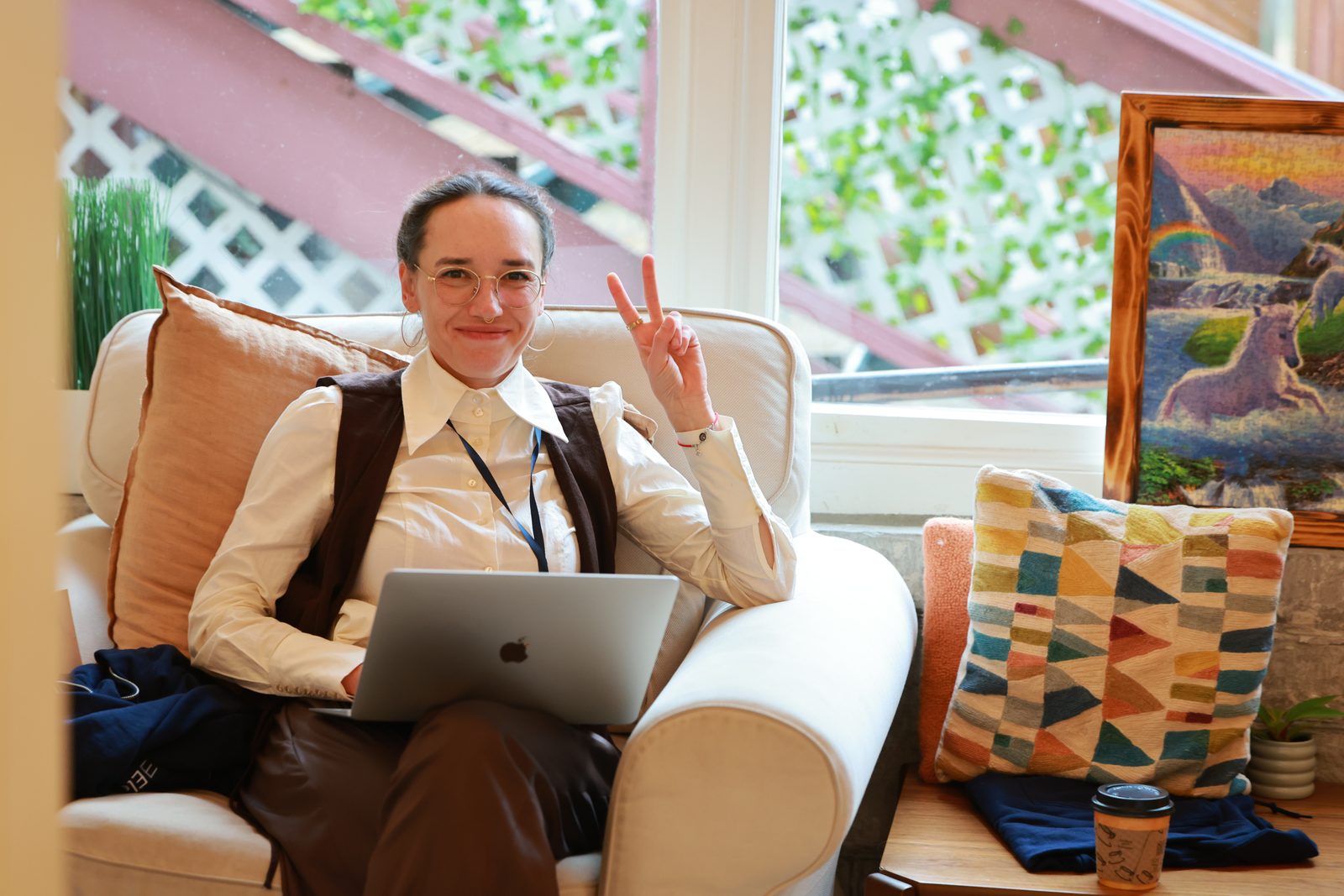 Anna Mikeda, seated with her laptop and raising a peace sign